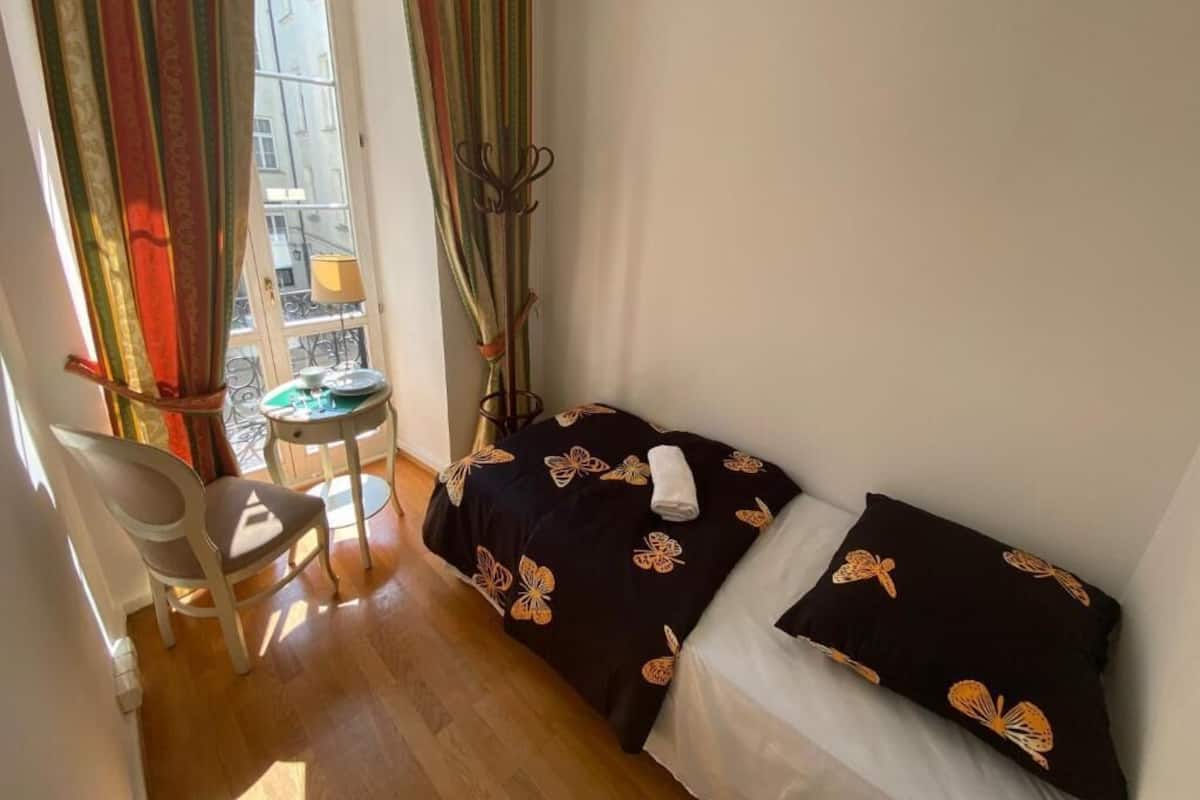 A small room with two beds, a chair, a table, and a window with curtains.