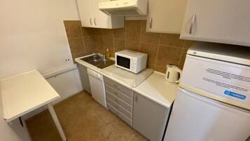 A compact kitchen with white cabinets, a microwave, a coffee maker, and a refrigerator.