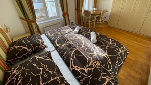 Un dormitorio con cama, cortinas, una mesita y sillas.