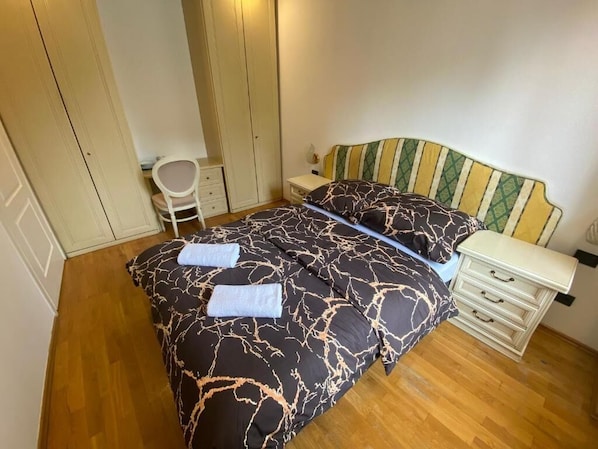 A bedroom with a bed, a bedside table, a chair, and a wardrobe.