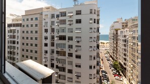 A high-rise building with multiple balconies, a view of the sea, and parked cars along the street. - 300 Meters From Copacabana Beach Nsc909 (Rio de Janeiro)
