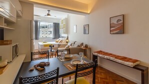 A modern dining area with a table set for two, a sofa, and a bench. - 300 Meters From Copacabana Beach Nsc909 (Rio de Janeiro)