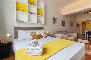 Habitación de hotel con cama, sofá, escritorio y estante con adornos.