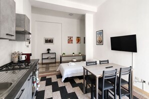 Una cucina compatta con piano cottura, lavello e un piccolo angolo ristoro con tavolo e sedie.