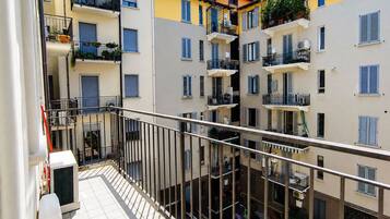 Un edificio residenziale a più piani con balconi, condizionatori d'aria e piante in vaso.
