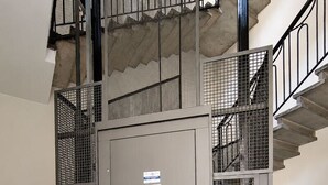 A grey elevator with a digital display, surrounded by a tiled floor and metal railings. - BIG Flat Goldoni [Duomo–M4–Linate] (Milan)