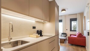 A modern kitchen with a stainless steel sink, a coffee maker, and a countertop with a box of tissues. - Numancia Apartments by Olala Homes (Madrid)