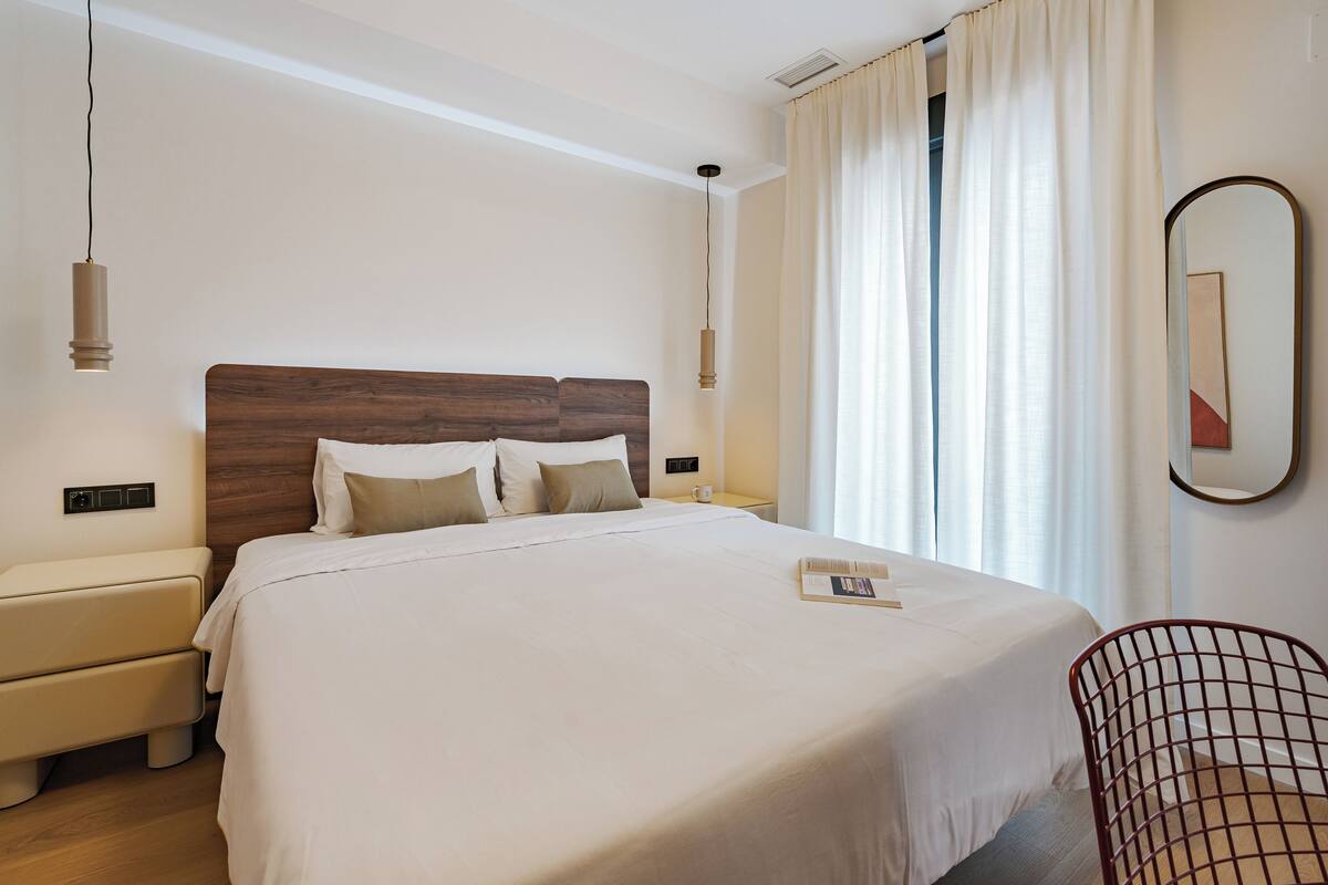 Een hotelkamer met een groot bed, nachtkastjes, een stoel en een spiegel.