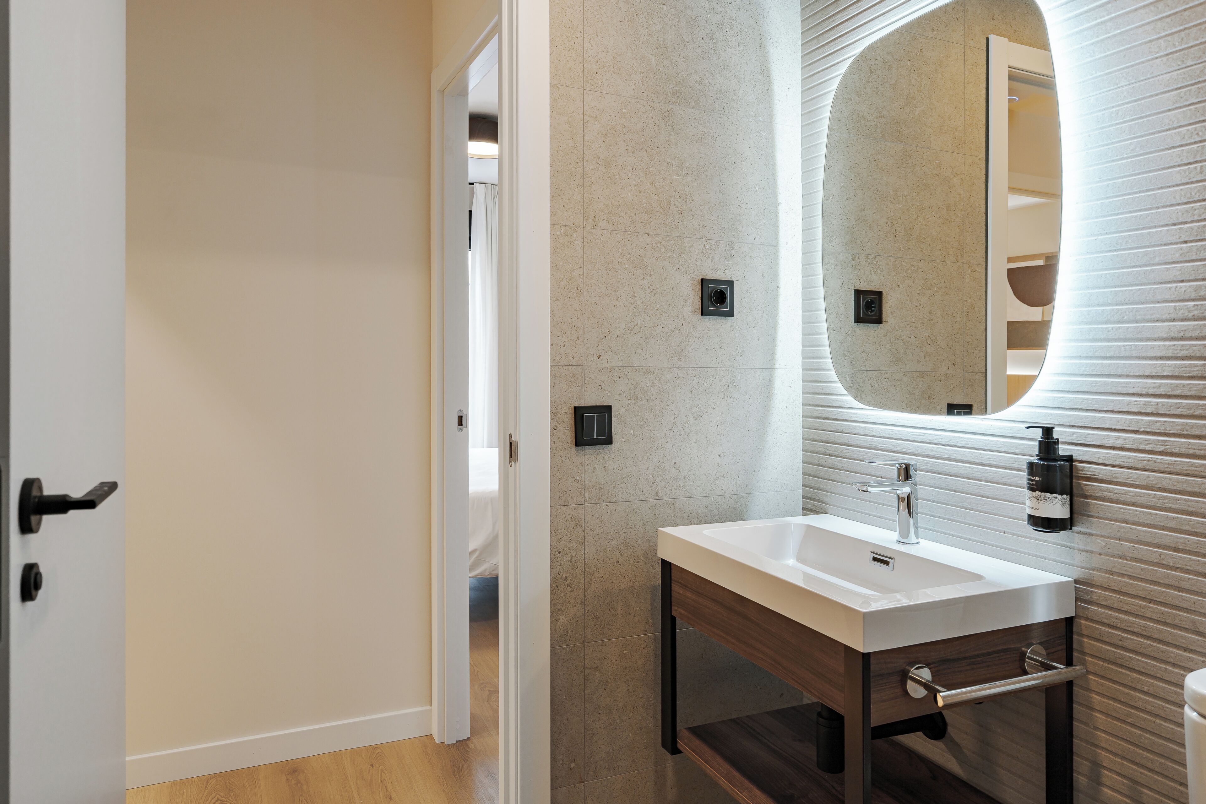 Une salle de bain moderne avec un lavabo blanc, un grand miroir et un meuble-lavabo en bois.