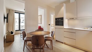 A modern kitchen with a dining area, wooden flooring, and a large window. - Numancia Apartments by Olala Homes (Madrid)