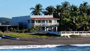 Una propiedad frente a la playa con un edificio de dos pisos, un balcón y vista al océano.