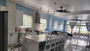 Una cocina moderna con una isla de mármol, armarios blancos y un comedor con sillas.