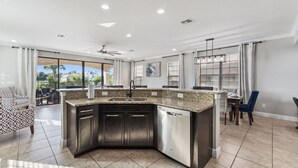Eine moderne Küche mit einer Granit-Arbeitsfläche, Edelstahlgeräten und einem Essbereich mit Tisch und Stühlen.
