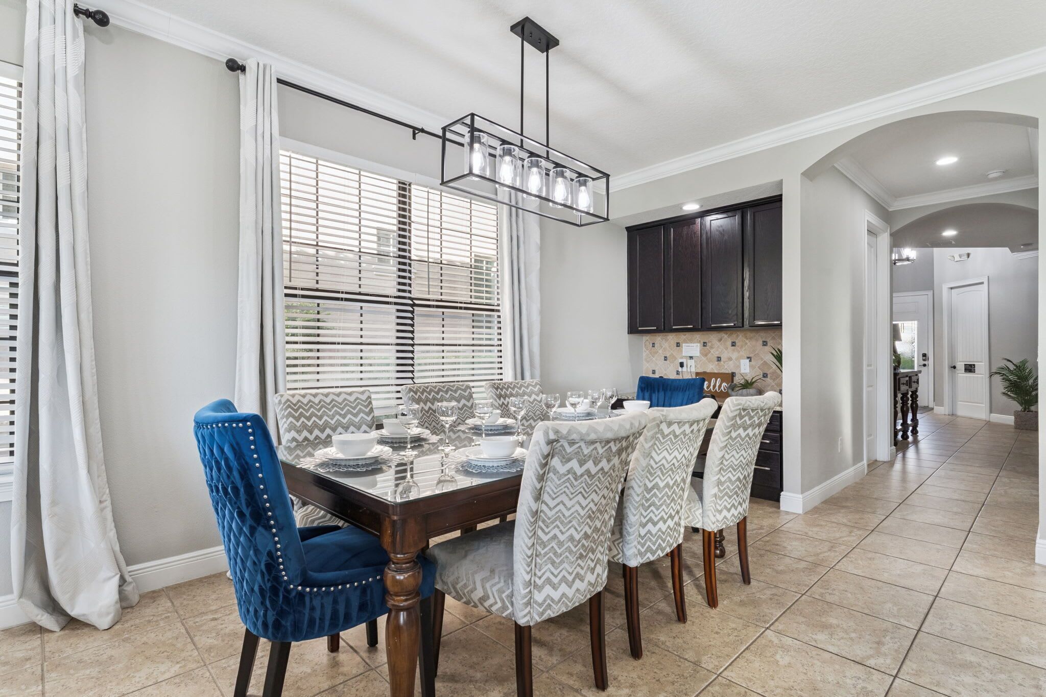 Comedor con una mesa rectangular dispuesta para seis personas, con sillas azules y estampadas a cada lado.