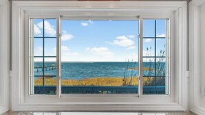 A room with a large window offering a view of the sea and a dock. - Lavinder House by Seaside Vacations & Sales! (Chincoteague Island)