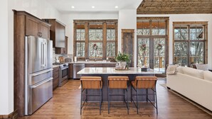 Una cocina moderna con armarios de madera, electrodomésticos de acero inoxidable y una isla grande con taburetes de bar.