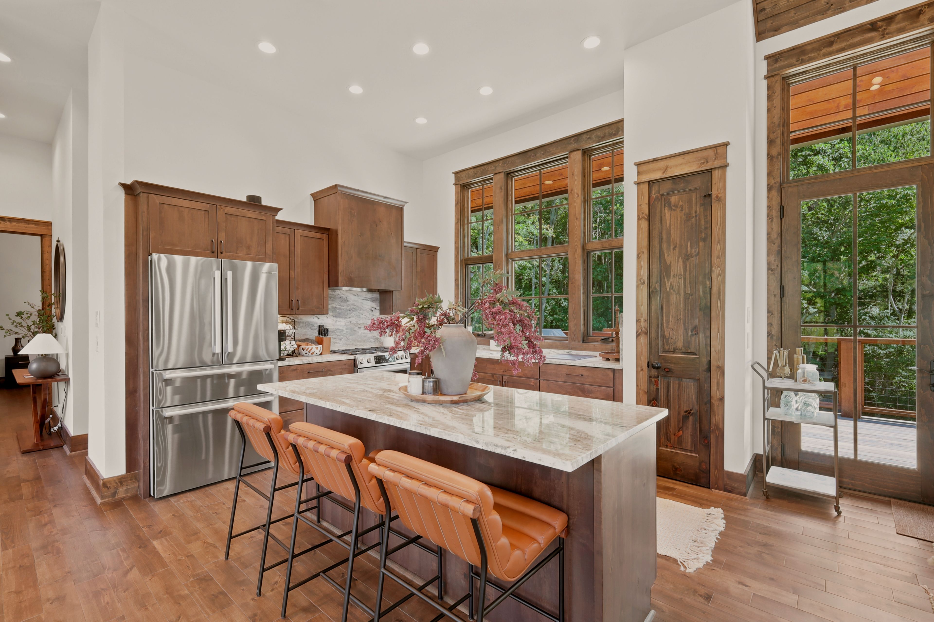 A modern kitchen with a large island, stainless steel appliances, and wooden cabinets.