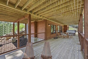 En træterrasse med pergola, udendørs møbler og et grillområde.