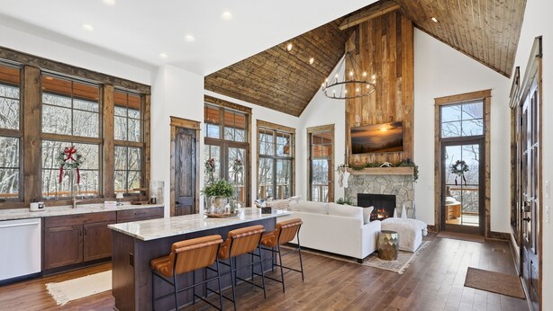 Una cocina amplia con una isla grande, taburetes de madera y una chimenea de piedra.
