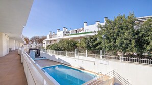 Una piscina con bordo piastrellato, ringhiera bianca e cielo azzurro.