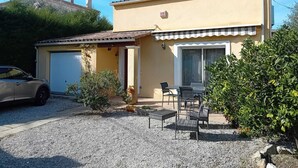 A two-story house with a garage, a patio with outdoor furniture, and a car parked in front. - Villa "La Farigoulo" with garden (Antibes)