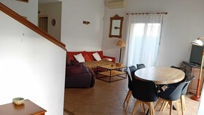 A living room with a sofa, a dining table with chairs, a lamp, and a staircase. - Villa "La Farigoulo" with garden (Antibes)