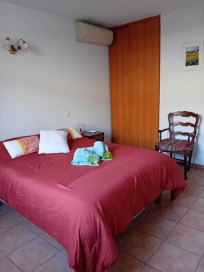 A bedroom with a red bedspread, a wooden chair, and a small bedside table. - Villa "La Farigoulo" with garden (Antibes)