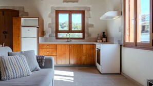 A compact kitchen with wooden cabinets, a built-in oven, and a window above the sink. - Vamos Villa (Apokoronas)