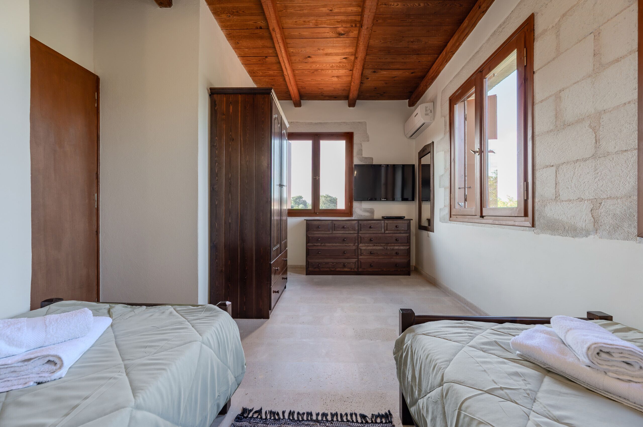 Une chambre avec deux lits, une armoire en bois, une commode et un téléviseur.