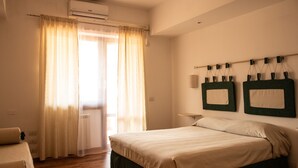 Una camera da letto con un letto, tende, condizionatore d'aria, una mensola a parete e un termosifone.