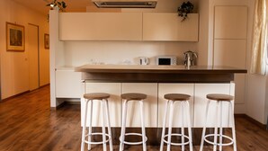 Una cucina con isola centrale, quattro sgabelli, un forno a microonde e un bollitore.