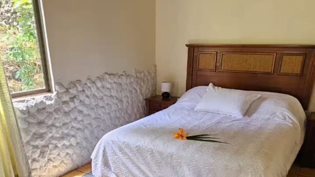 Una habitación con una cama, una mesita de noche y un ventanal.