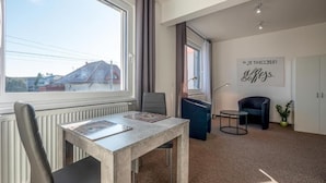 Une pièce moderne comprenant une table à manger, une chaise, une petite table avec une lampe et une plante en pot.