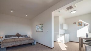 Une chambre d’hôtel moderne équipée d’un lit, d’un bureau et d’une kitchenette.