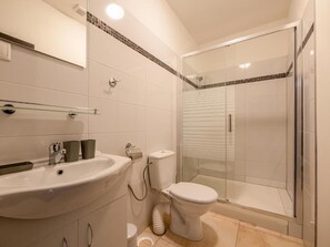A modern bathroom with a glass-enclosed shower, a white sink with a mirror above it, and a toilet. - Penzión ARIES (Nitra)