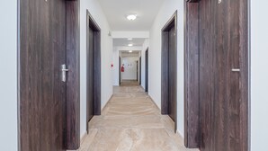 Un couloir avec des portes en bois foncé, un revêtement de sol en carrelage beige et des murs blancs.