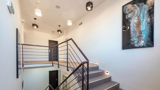 Un escalier moderne avec des rampes en métal et un éclairage intégré, menant à un deuxième étage.