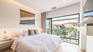 Een moderne hotelkamer met een groot bed, een nachtkastje, een balkon met een tafel en stoelen, en uitzicht.