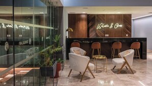 Een moderne receptie met een houten receptiebalie, witte stoelen en een glazen wand met een neonbord.
