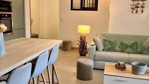 A modern living room with a wooden dining table, blue chairs, a grey sofa, and a coffee table. - Apartment in Maghjina near port and town center (Porto-Vecchio)