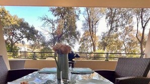 An outdoor dining area with a glass table, wicker chairs, and a view of trees. - Apartment in Maghjina near port and town center (Porto-Vecchio)