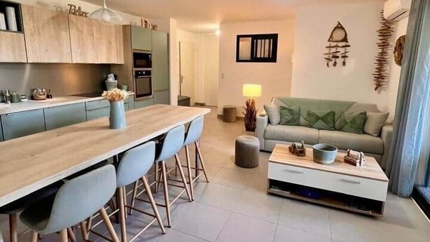 A modern kitchen with a central island, a dining area with chairs, a sofa, and a coffee table. - Apartment in Maghjina near port and town center (Porto-Vecchio)