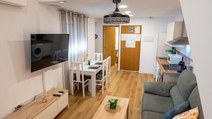 En kompakt bolig med spiseplads, sofa, fjernsyn og tekøkken.
