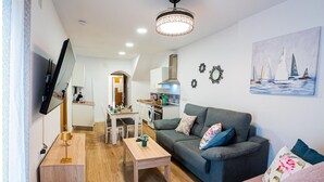 Un salon moderne avec un canapé gris, une table basse en bois et un téléviseur fixé au mur.