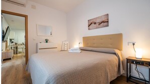 Une chambre à coucher bien rangée, avec un grand lit, une table de chevet avec une lampe, un miroir et un tableau accroché au mur.