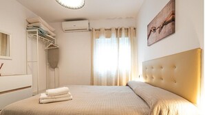 Een slaapkamer met een groot bed, een kledingkast, een airconditioning en een schilderij aan de muur.