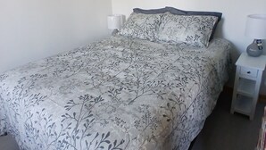 Un dormitorio con una cama, una mesita de noche, una lámpara y un cuadro en la pared.