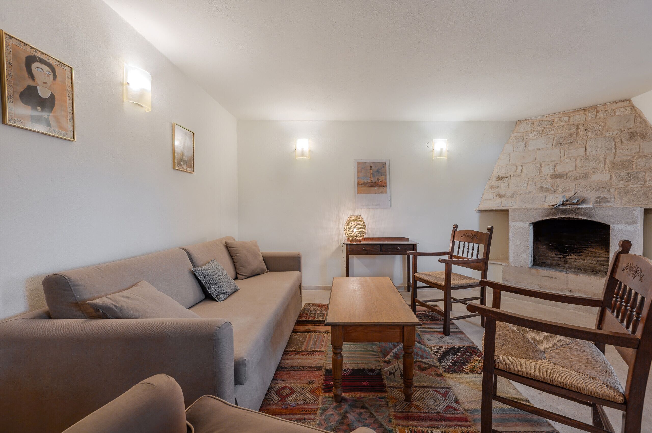 A living room with a sofa, wooden table, chairs, a fireplace, and patterned rugs.