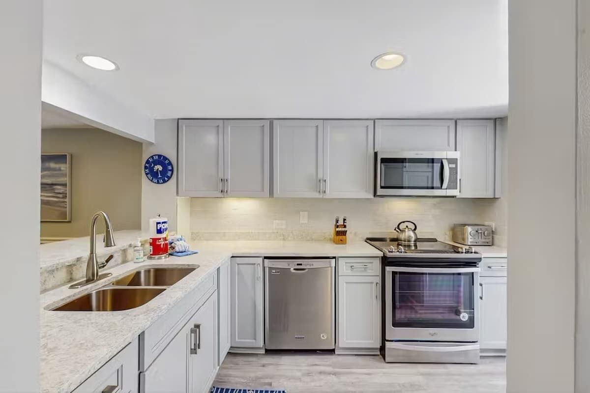 A modern kitchen with white cabinets, stainless steel appliances, and a dishwasher.
