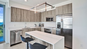Una cocina moderna con lavavajillas integrado, electrodomésticos de acero inoxidable y una isla grande con taburetes de bar.